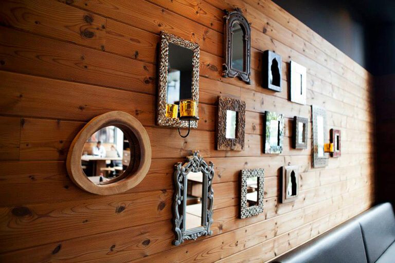 Assortiment de cadres de différentes formes et couleurs installés sur une mur de bois