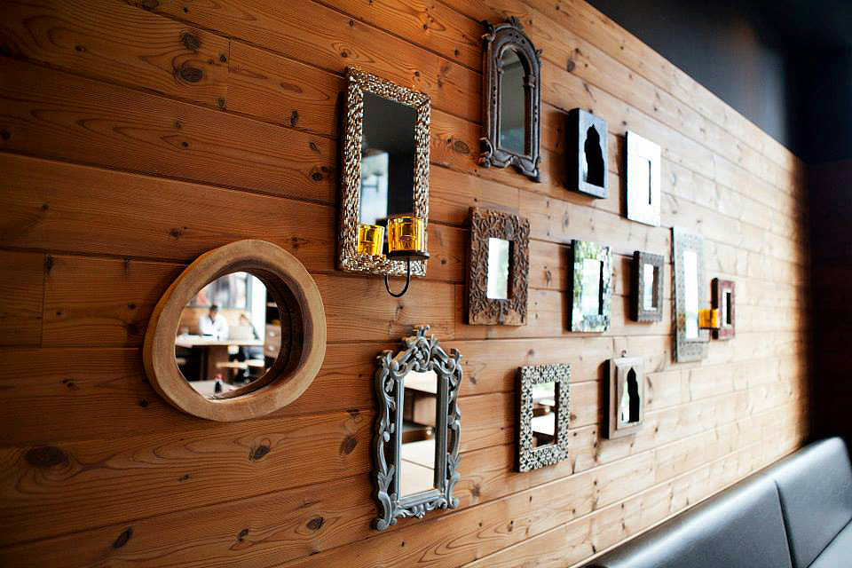 Assortiment de cadres de différentes formes et couleurs installés sur une mur de bois