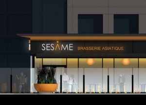 Façade extérieure du restaurant SESAME avec une vue sur la terrasse en fin de soirée avec l'enseigne lumineuse