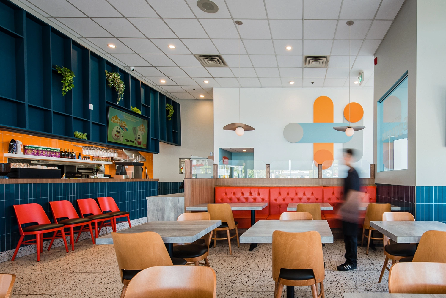 Design intérieur restaurant Eggsquis Greenfield Park – Aménagement salle à manger moderne avec banquettes orange et comptoir en céramique bleue par Dany Perron et EXA Design.